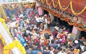Baba's court decorated with colorful flowers and lights, devotees thronged